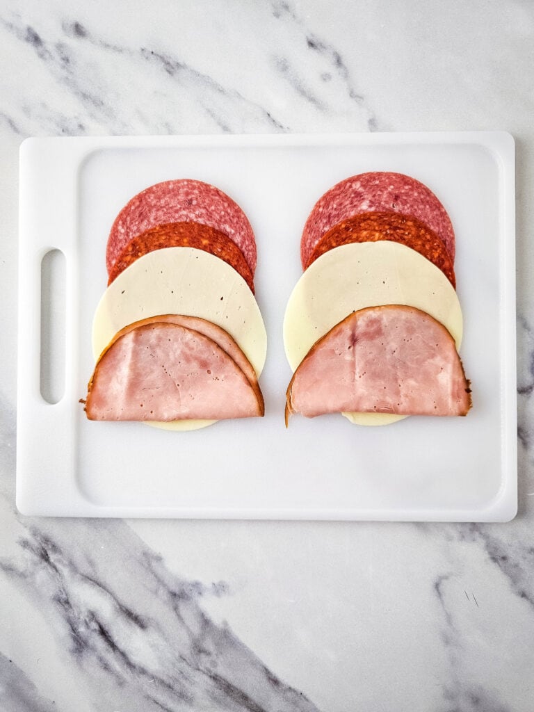 A picture of two rows of Italian meats and cheese.