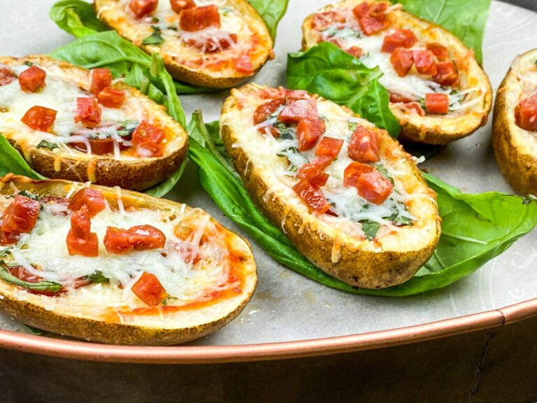 A picture of pizza stuffed baked potato skins on beds of lettuce leaves.