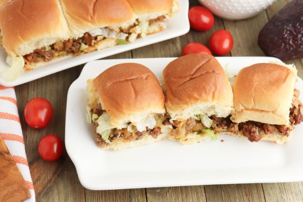 A picture of three taco sandwich sliders on a plate with grape tomatoes on the side.