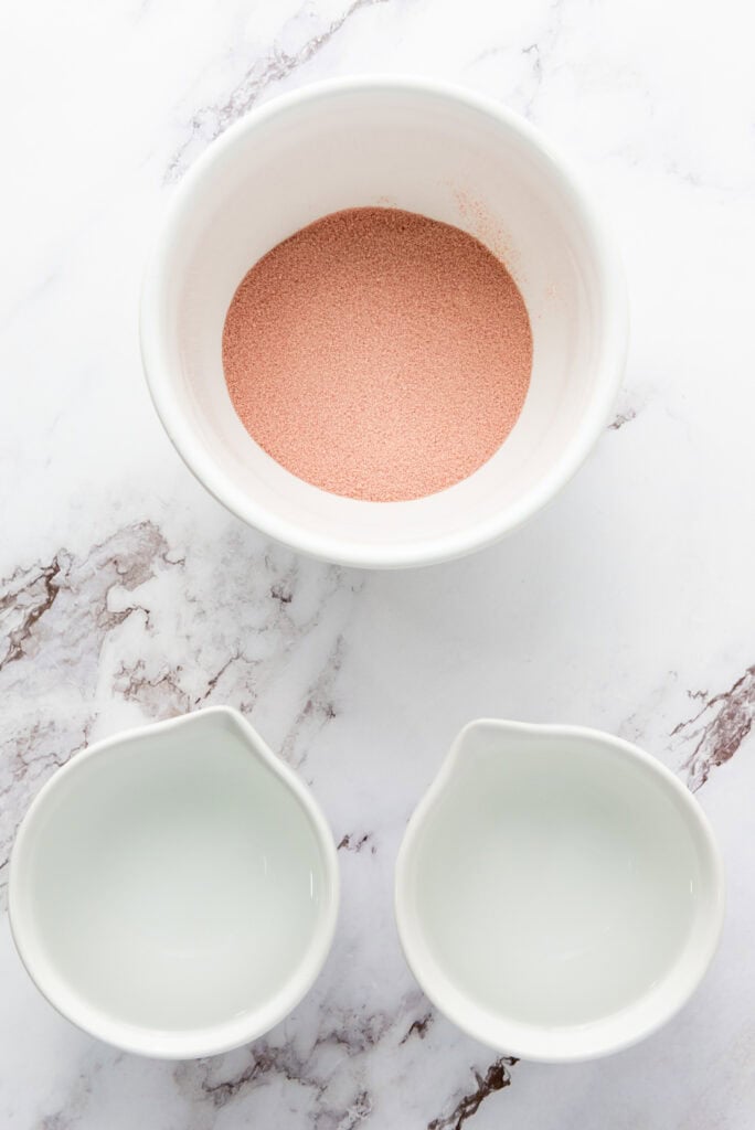 red jello powder and two cups of water on a table