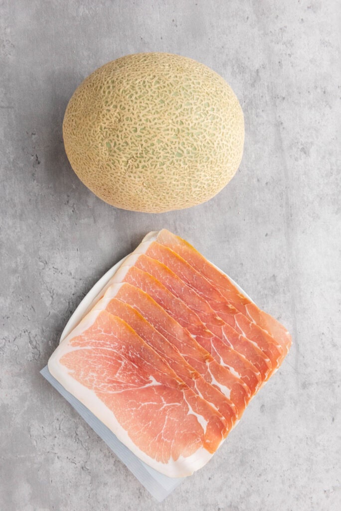 cantaloupe and prosciutto on a gray background