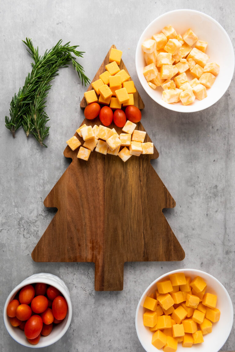 Two layers of cheese and one layer of tomatoes atop a christmas tree cheese board