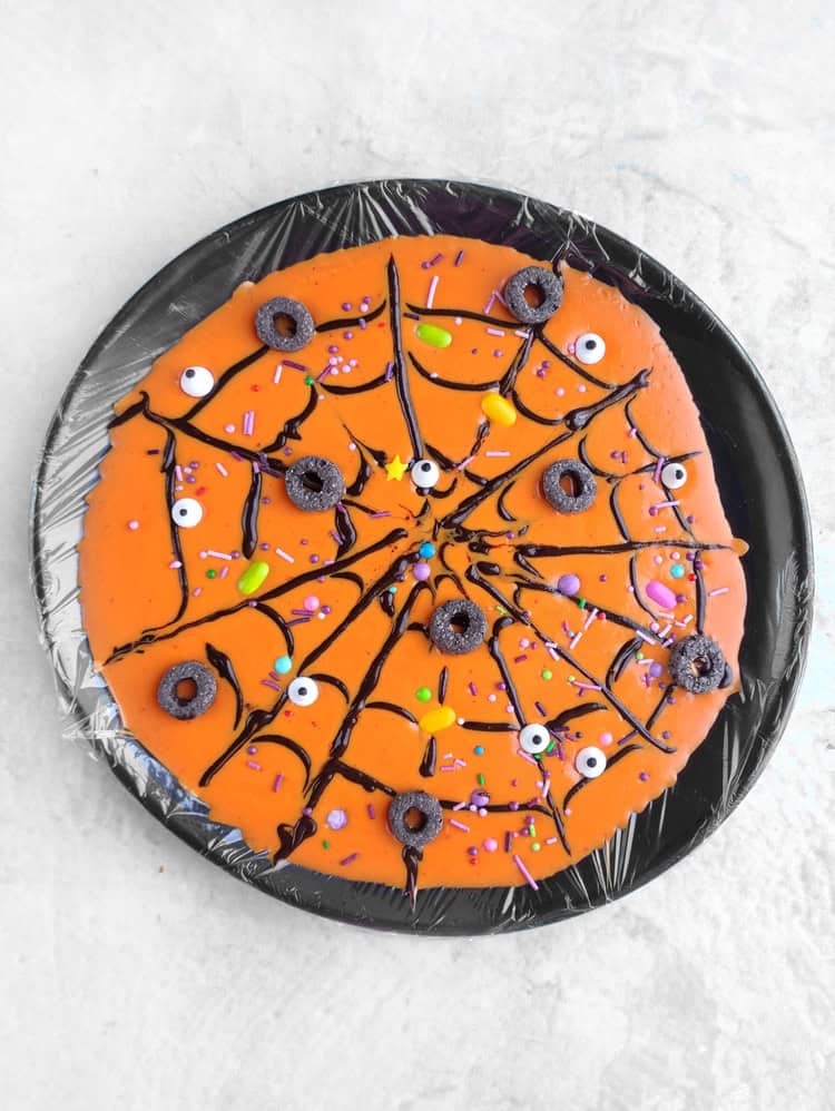 melted, dyed orange chocolate with black cereal rings, sugar eyes, sprinkles, and small candy