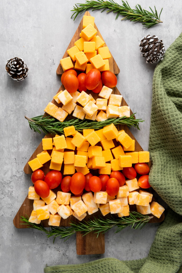 christmas charcuterie board with tomatoes, rosemary and cheese blocks