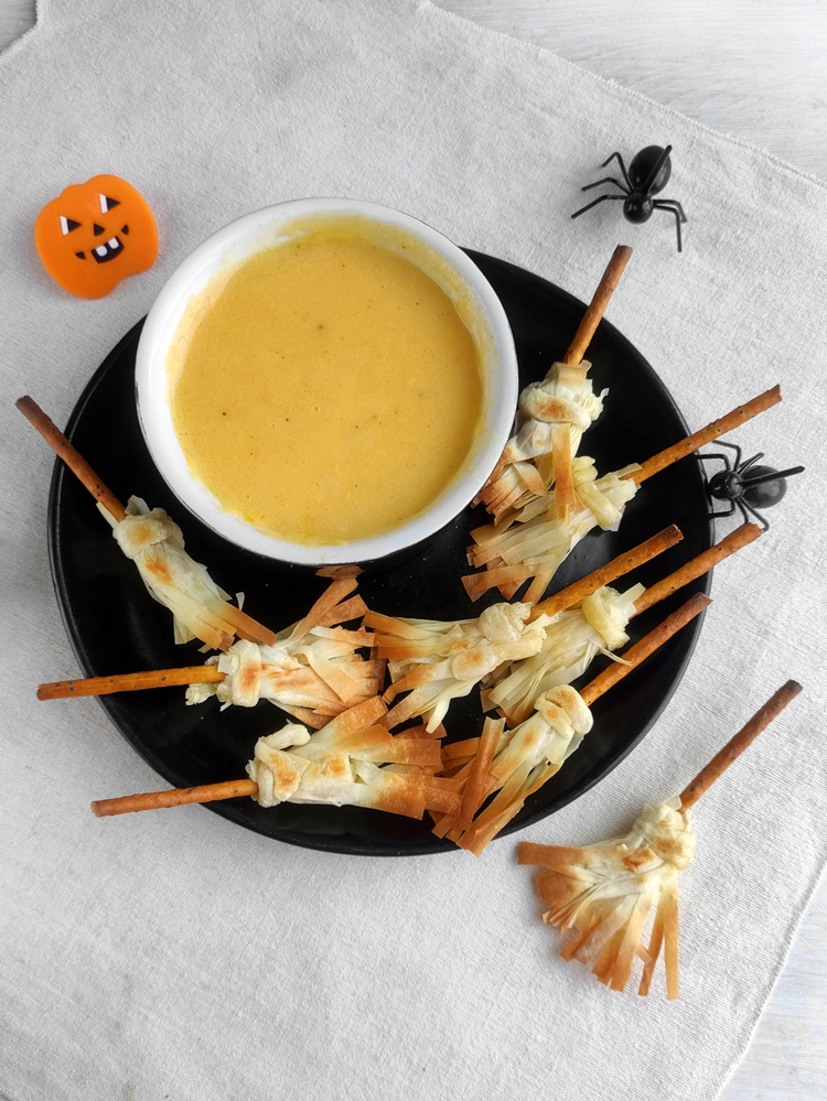 Witch's brooms and cheese dip with toy spiders.