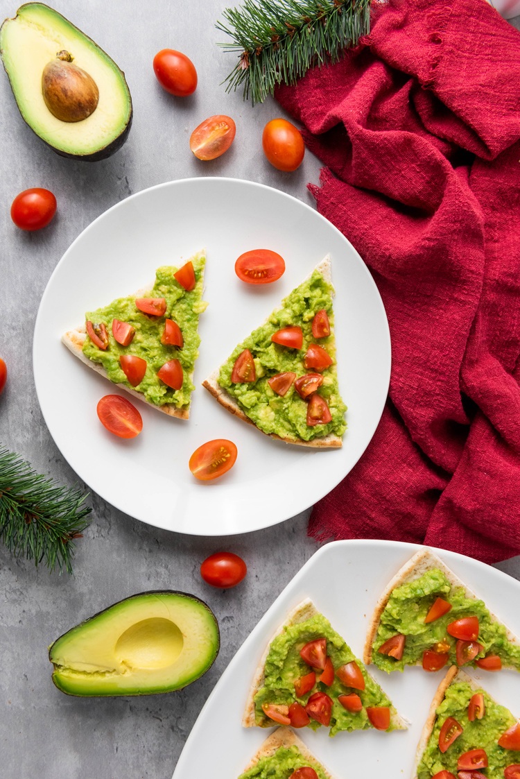 festive avocado pita bread with tomatoes on a serving platter and red cloth