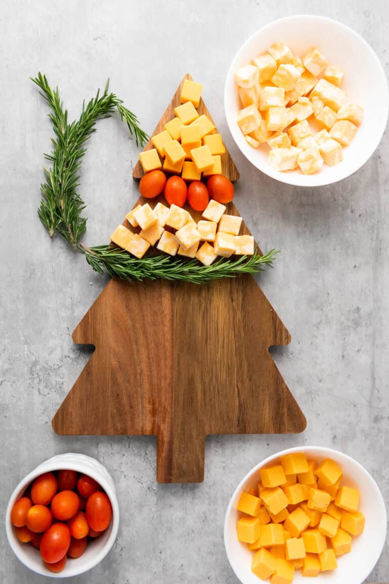 layers of gouda and colby cheeses, tomatoes and rosemary on xmas tree board