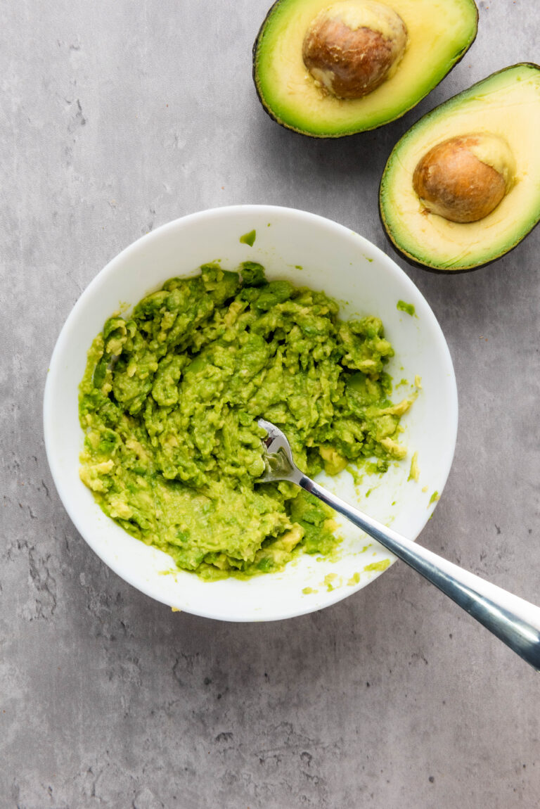 mashed avocados in a medium bowl on a gray table