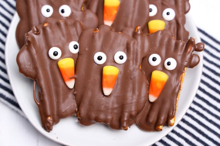 turkey chocolate pretzels on a white plate atop a blue and white striped kitchen towel