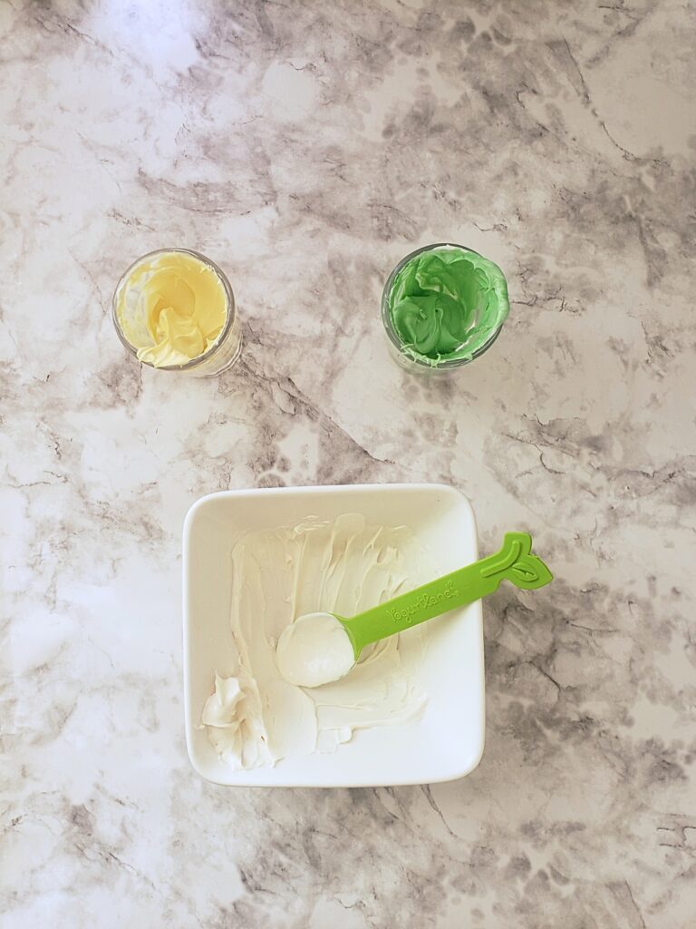 white, green and yellow candy melts in bowls on a countertop