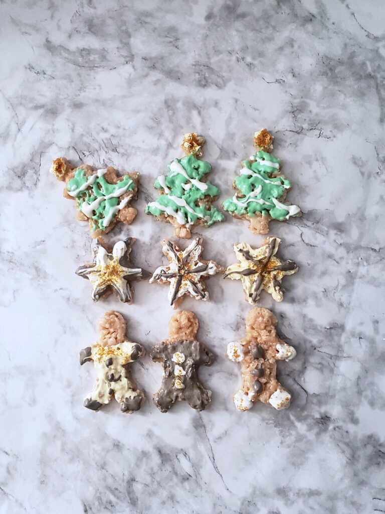 nine christmas-themed rice krispies treats on a marble table