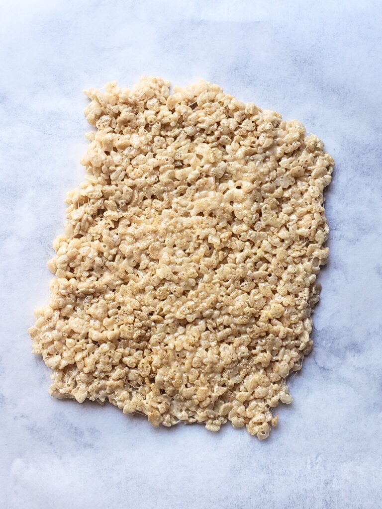 rice krispies treats spread into a thin rectangle on a parchment paper