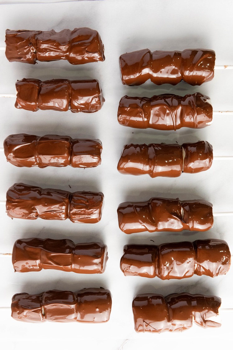 Hold each stick and dip all three marshmallows into the melted chocolate