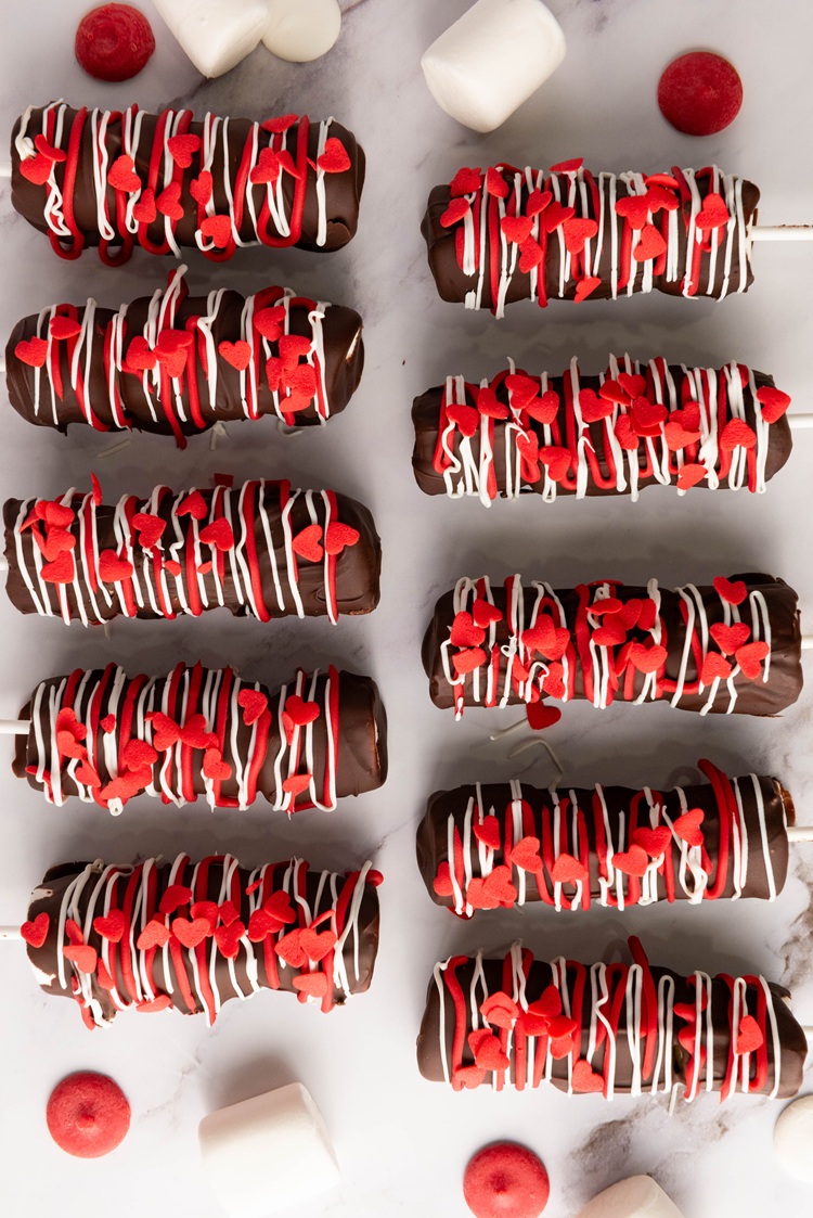 Melt the red and white candy melts separately, drizzle them over the pops, and sprinkle with little red hearts