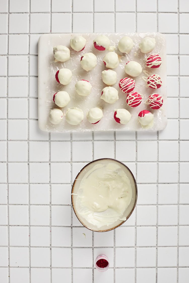 A set of red velvet truffles dipped or drizzled in white candy melts.