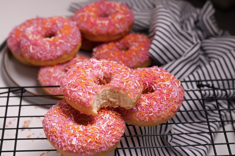 A picture of donuts with pink and orange sprinkles.