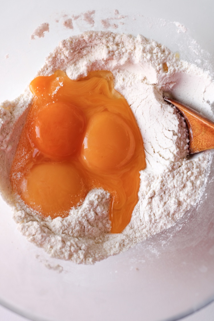 A picture of eggs in a bowl combined with dry ingredients to make donuts.