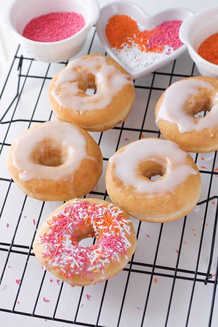 A picture of donuts topped with icing and sprinkles.