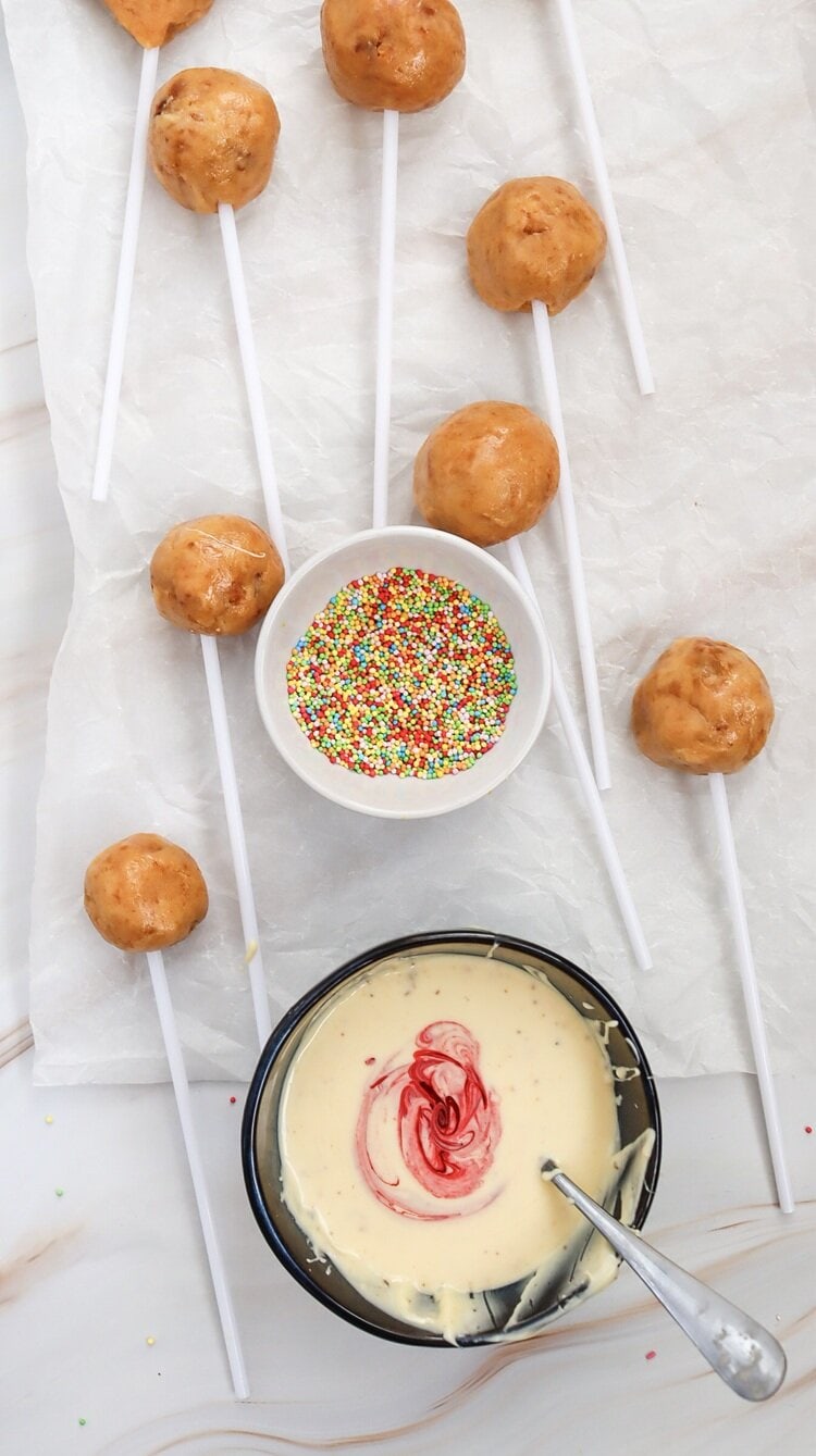 A picture of cake pops and a bowl of frosting with red food coloring added.