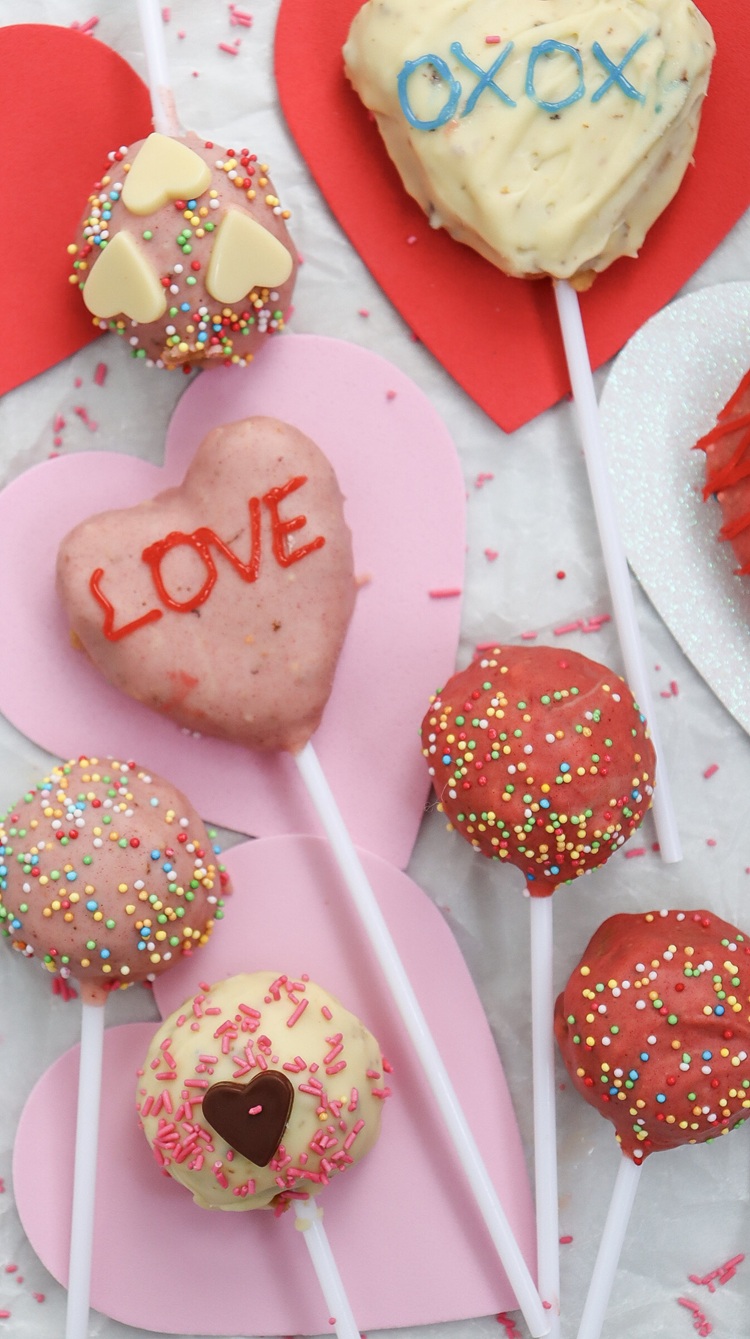 A picture of several Valentine's Day cake pops on heart shaped paper.
