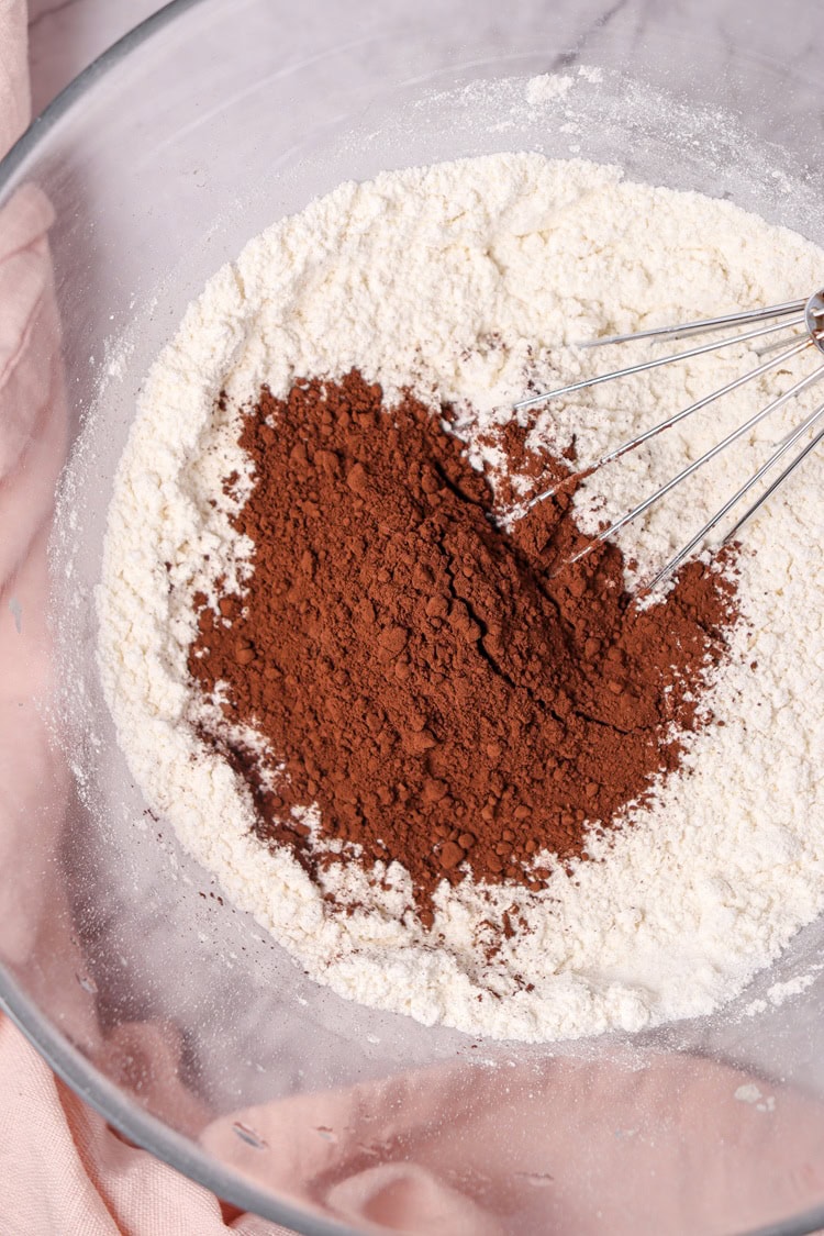 A picture of cocoa powder added to dry cake ingredients.