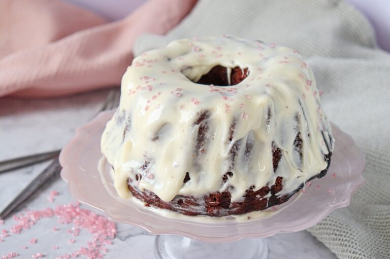 A picture of a whole red velvet cake with cream cheese frosting and peppermint sprinkles.