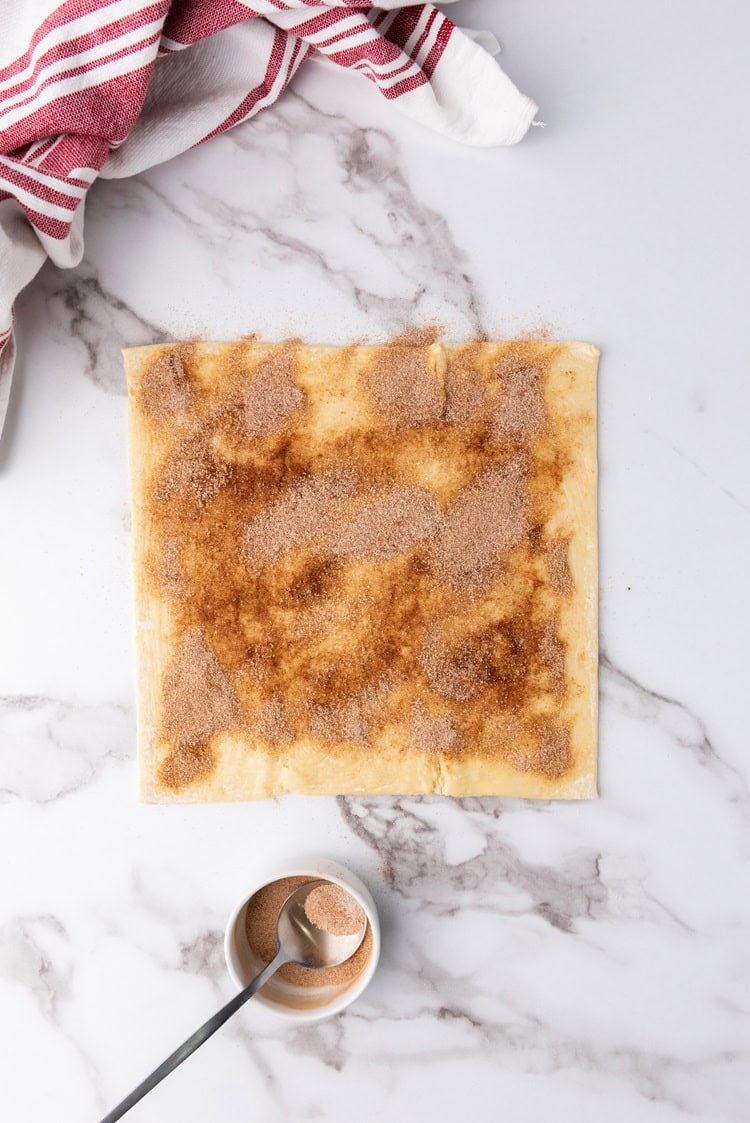 A picture of puff pastry sheets brushed with butter, cinnamon, and sugar.