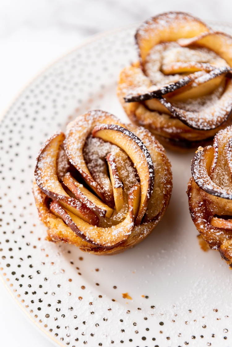 A zoomed in picture of a puff pastry apple rose dusted with powdered sugar.