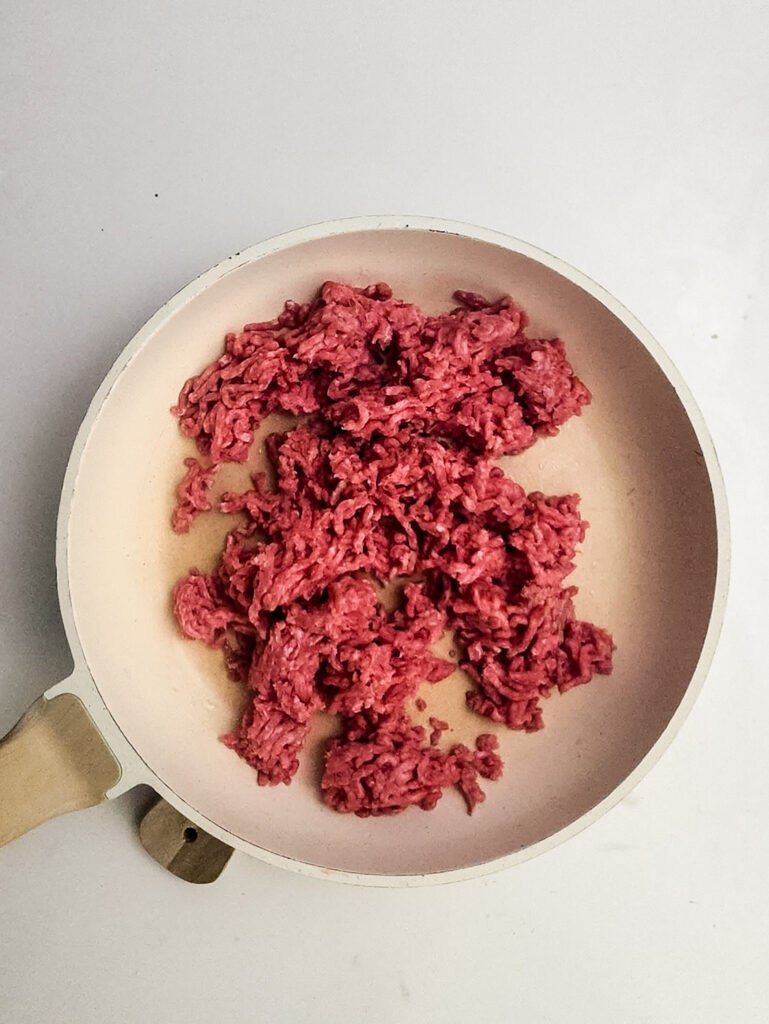 A picture of raw ground beef in a skillet.