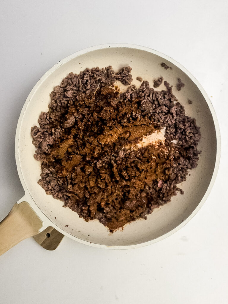 A picture of cooked ground beef in a skillet with taco seasoning.