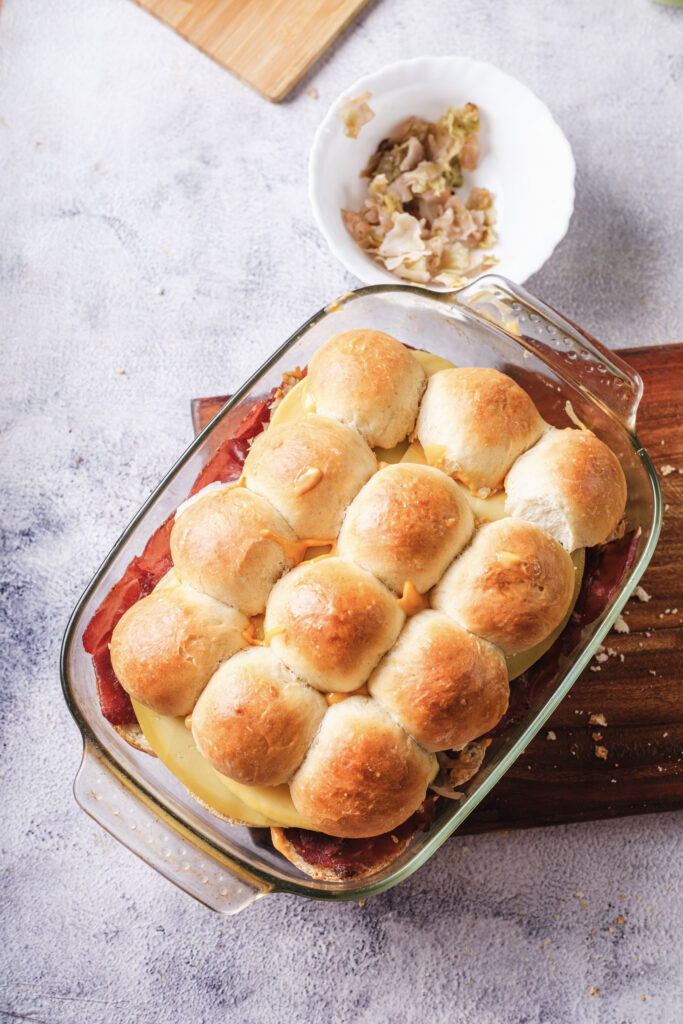 A picture of uncooked reuben sliders assembled in a baking pan.