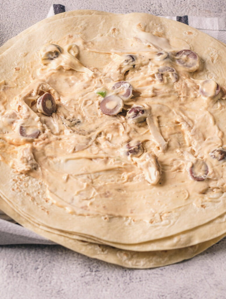 A picture of a chicken and cream cheese mixture spread across a flour tortilla.