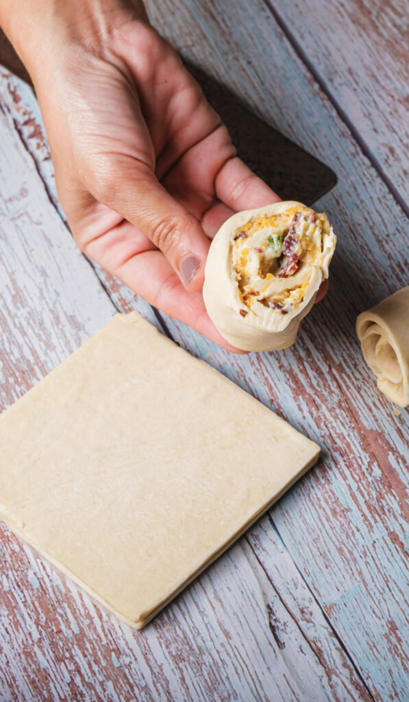 A picture of a puff pastry cut in two, with a hand holding one half to show the filling in the middle.