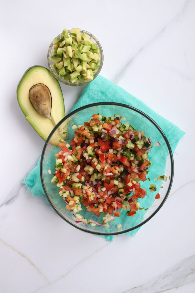 A picture of red onion, jalapeños, tomatoes, cucumber, and cilantro mixed together in a bowl.
