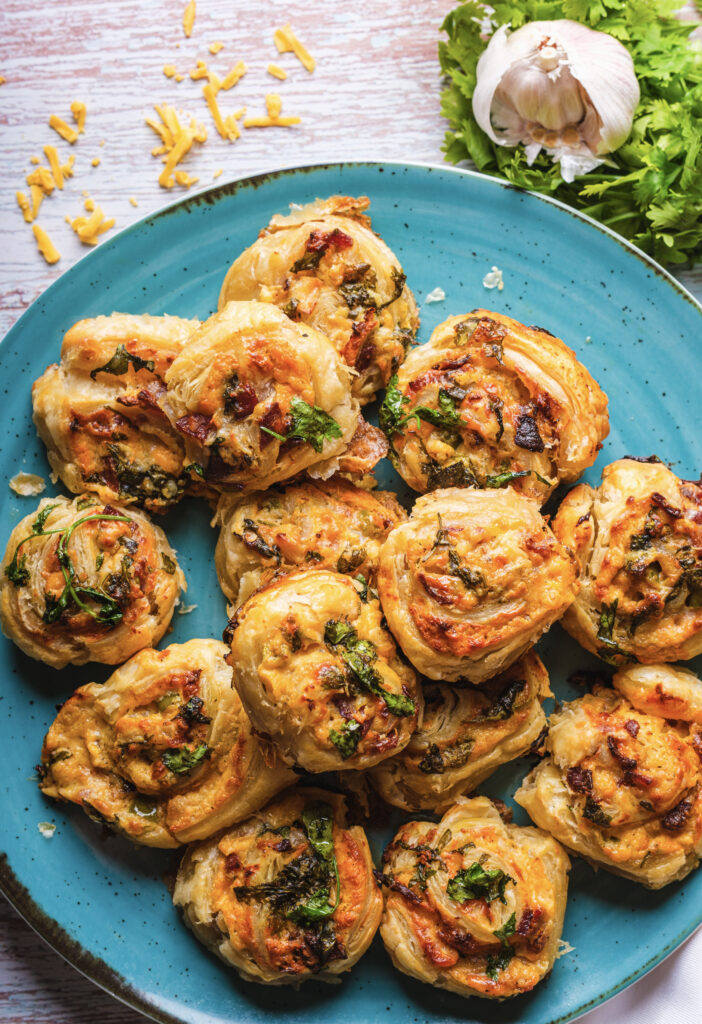 A close up picture of jalapeño popper pinwheels stacked together on a plate. 