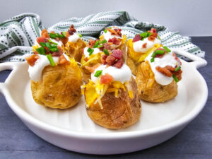 A picture of a set of loaded baked potato bites on a white plate.