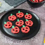 A picture of a tray of candy coated pretzels decorated to resemble apples.