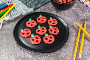A picture of a tray of candy coated pretzels decorated to resemble apples.
