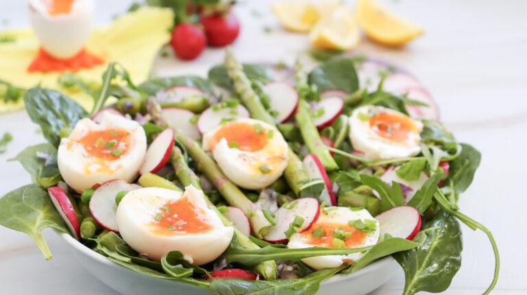 A picture of asparagus and pea salad with soft boiled eggs.