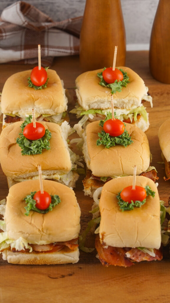 A picture of assembled blt sliders topped with a small piece of kale and a cherry tomato.