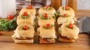 A picture of three columns of blt slider sandwiches topped with cherry tomatoes.