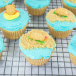A picture of beach themed cupcakes on a wire rack.
