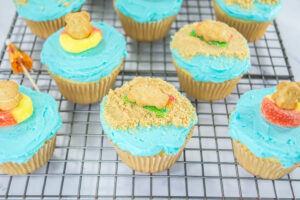 A picture of beach themed cupcakes on a wire rack.