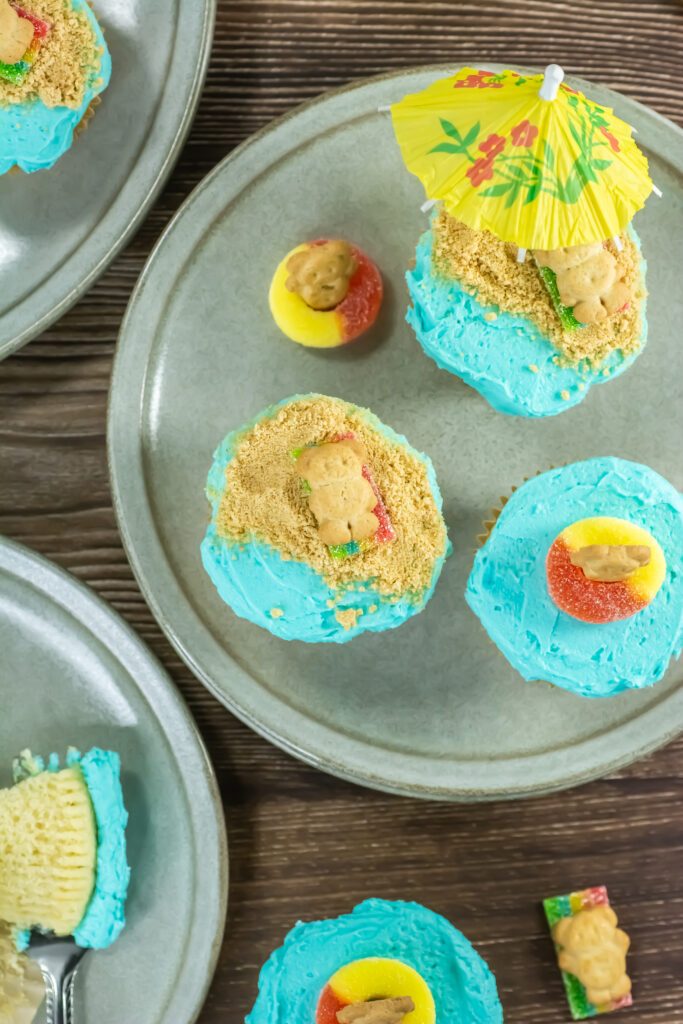 A picture of cupcakes decorated with cookies, candy, and mini umbrellas.