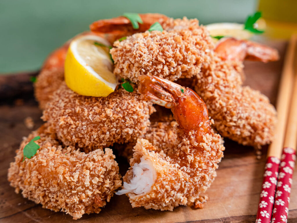 A picture of fried shrimp with a bite taken out of one.