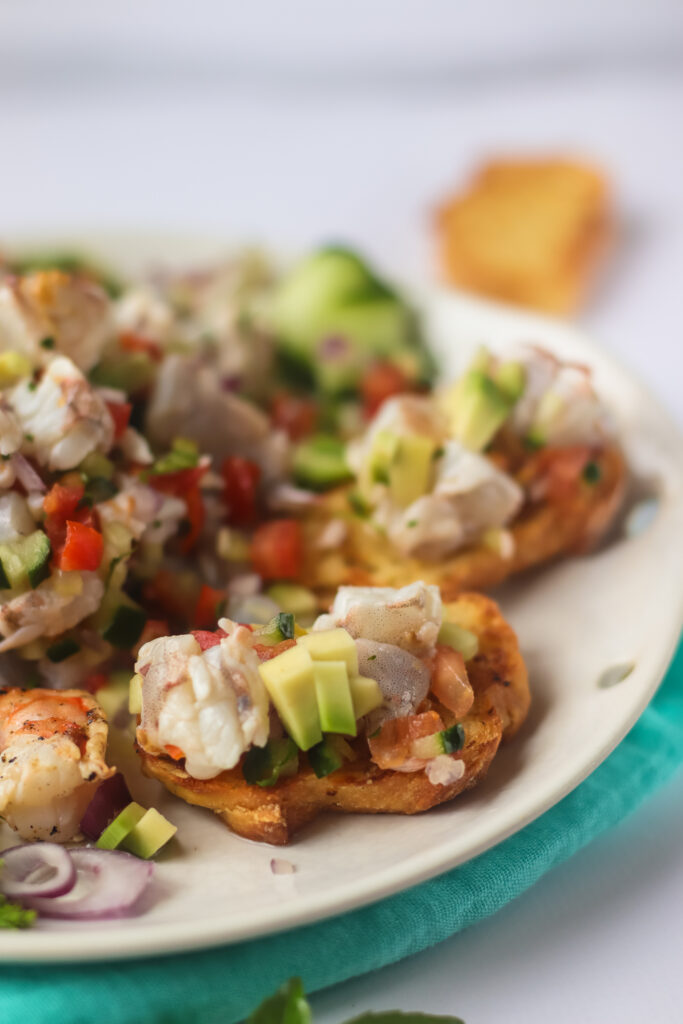 A picture of pieces of toasted bread topped with shrimp ceviche.