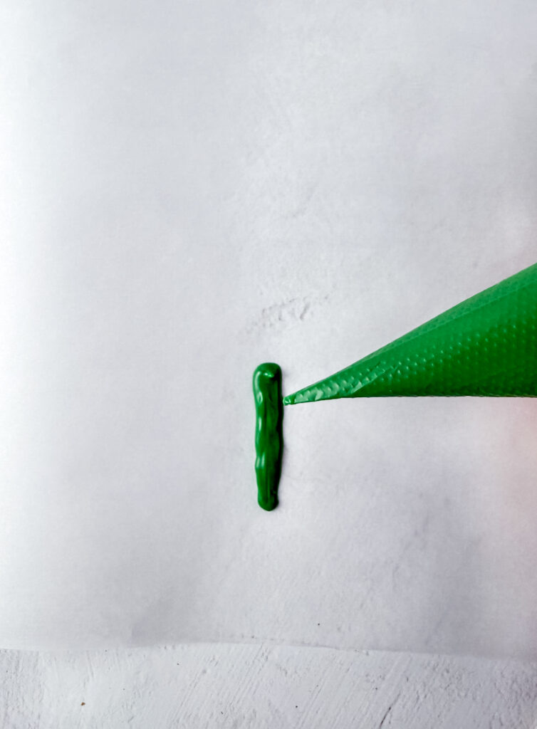 A picture of green frosting being pushed out of a piping tube.