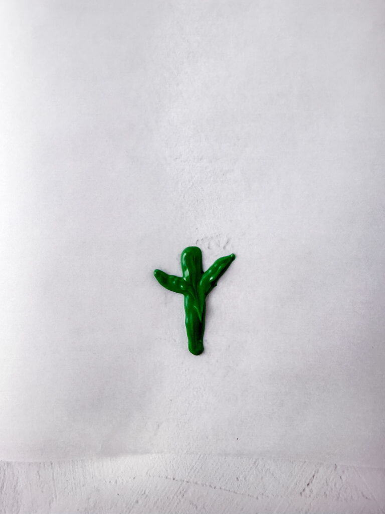 A picture of green frosting in the shape of a carrot frond.