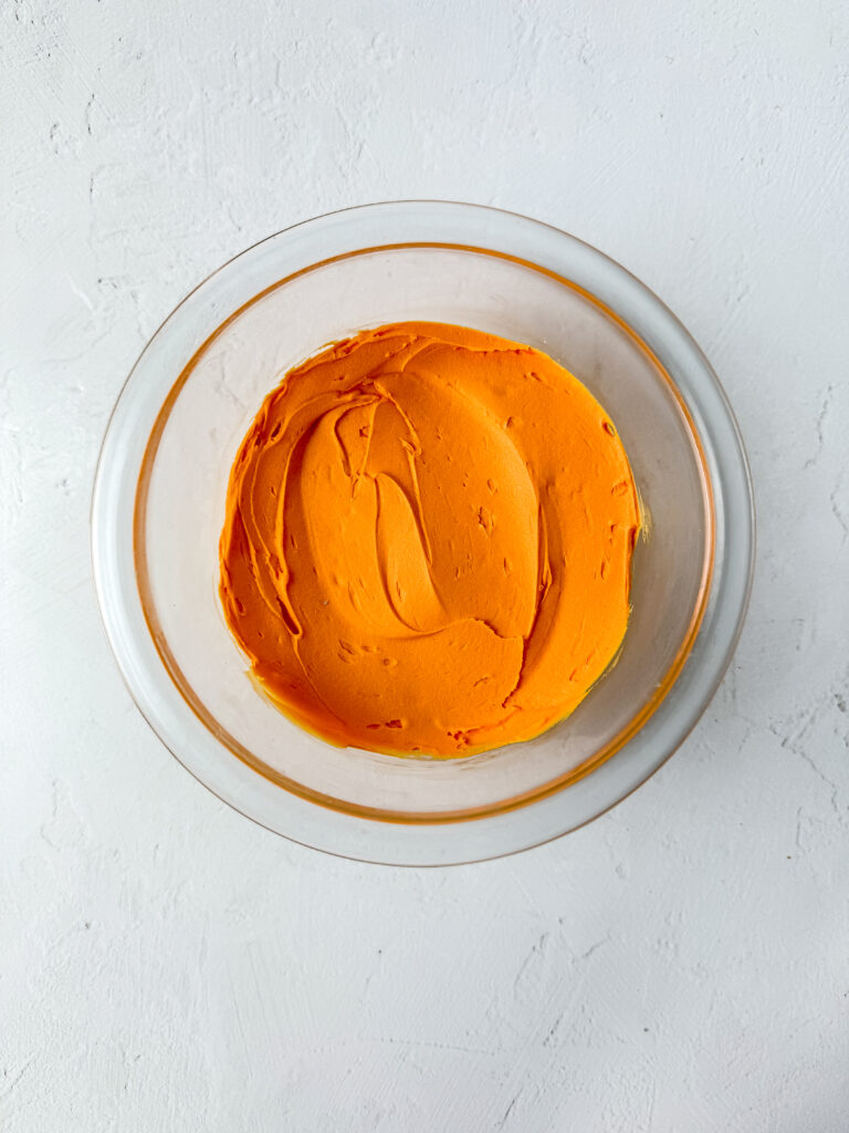 A picture of orange buttercream in a glass bowl.