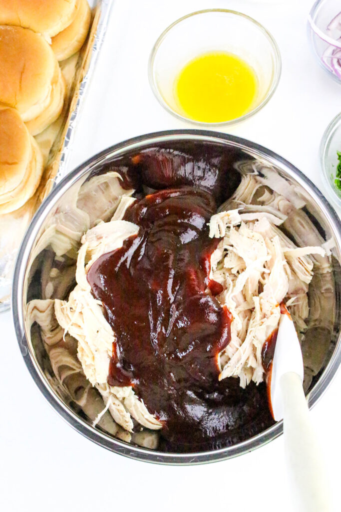 A picture of shredded chicken and barbecue sauce unmixed in a bowl.